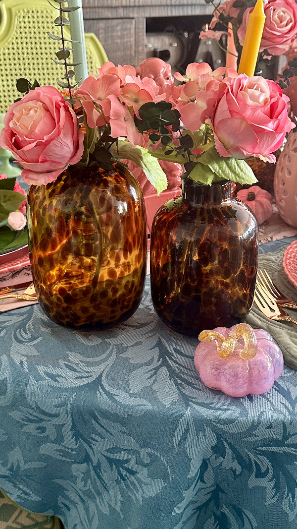 a pair of tortoise shell glass vases with pink roses on a styled tablescape