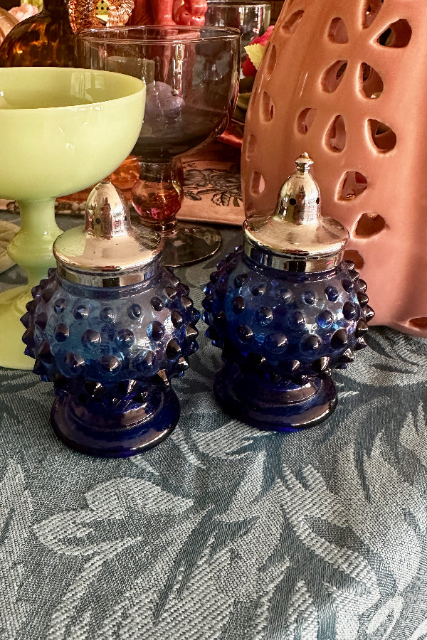 Vintage Hobnail Salt and Pepper Shakers in blue glass with silver tops displayed on a styled table