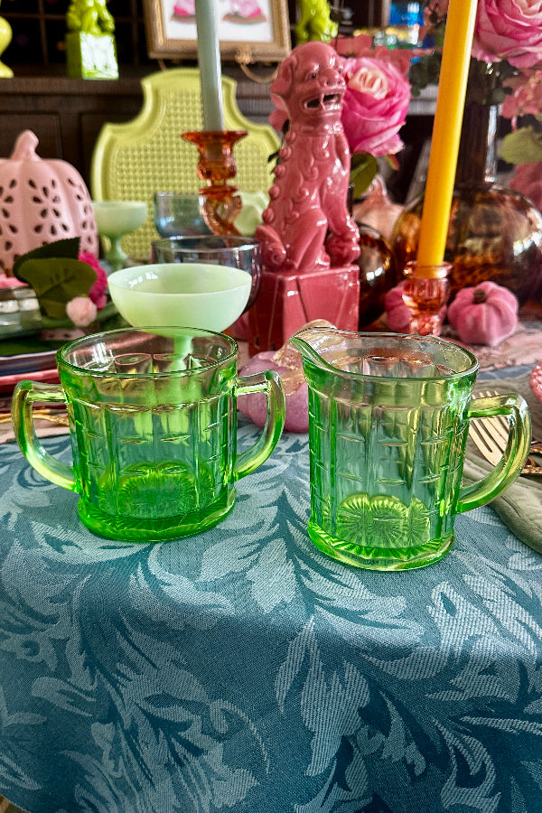 Vintage Sugar and Creamer Set -Uranium Glass in a bright green color with handles that glow under a UV light and styled on a dining table.