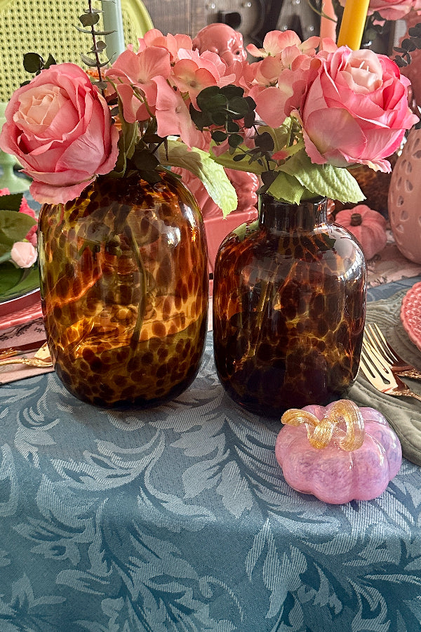 a pair of tortoise shell glass vases with pink roses on a styled tablescape